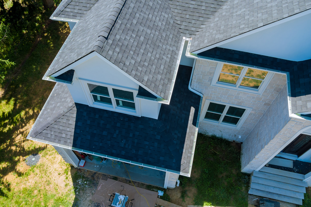 Aerial view of a newly constructed home with a rooftop featuring asphalt shingles and multiple roof lines
